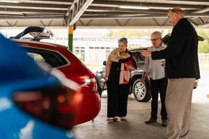 Older couple discussing their vehicle with a professional used car buyer during an inspection