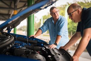 Used car buyer inspecting the engine of a blue car before making a purchase offer